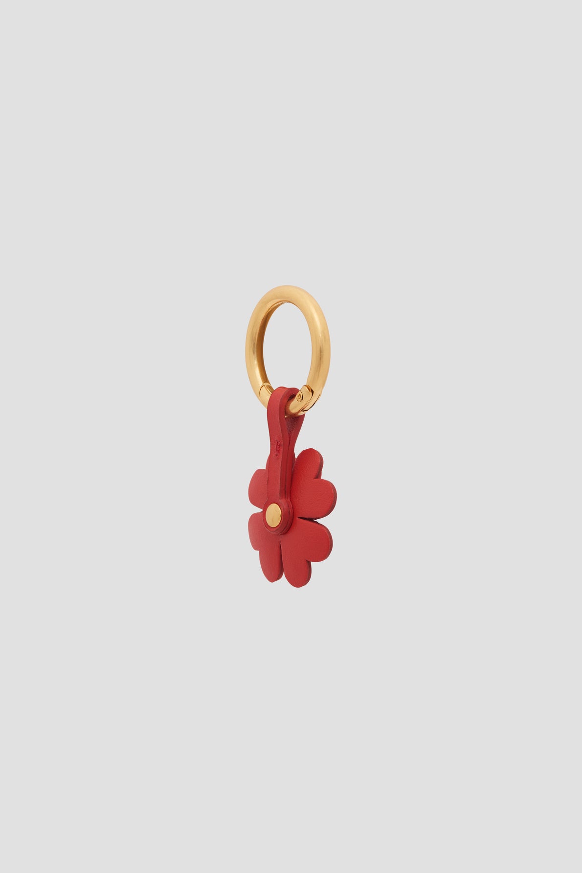 A gold circular keyring holding a red leather flower-shaped charm en cuir with visible petal details, displayed on a plain light gray background. This bijou luxe accessory adds an elegant touch, making it a perfect porte-bonheur for everyday style.