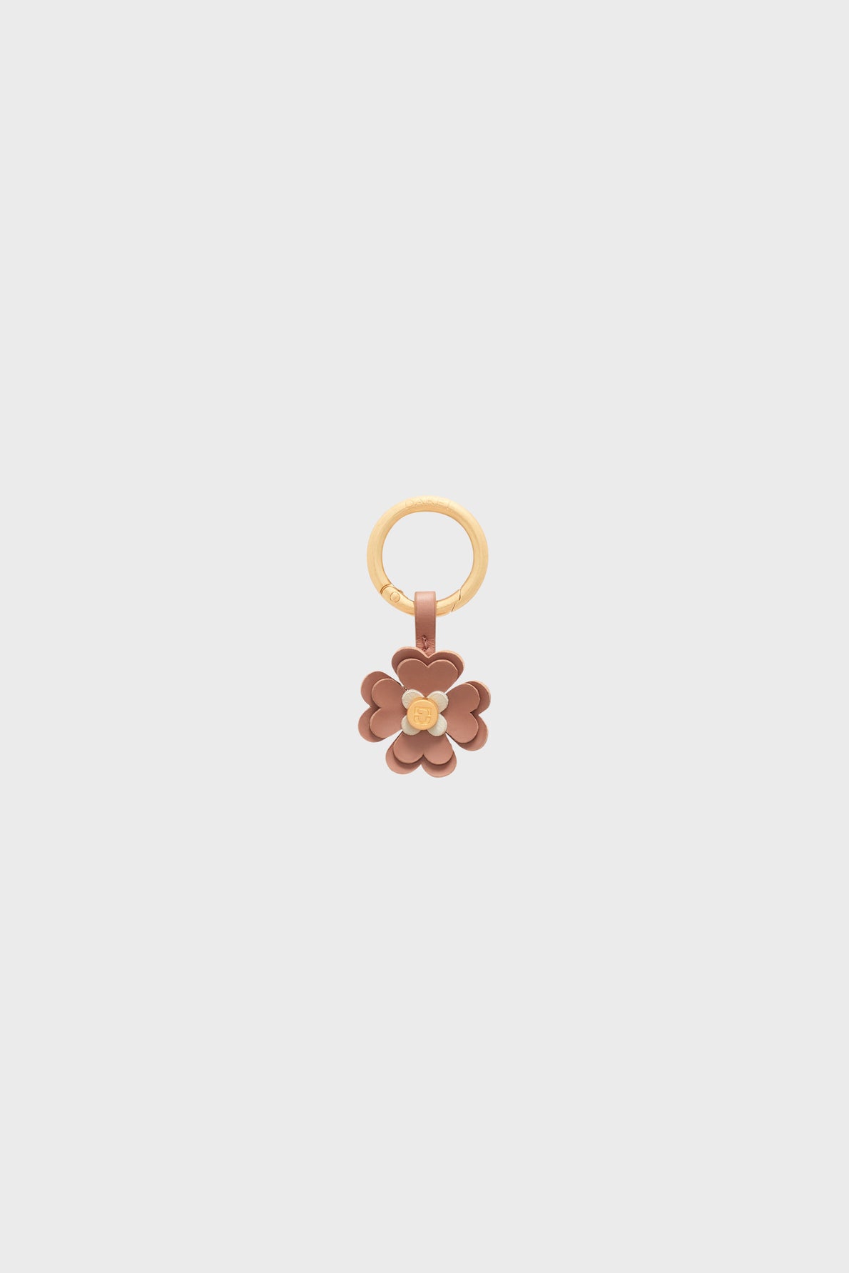 A gold keyring with a flower-shaped charm en cuir in shades of brown and beige, featuring layered petals and a small gold center, set against a plain light gray background—a unique bijou charm that makes a delightful porte-bonheur accessory.