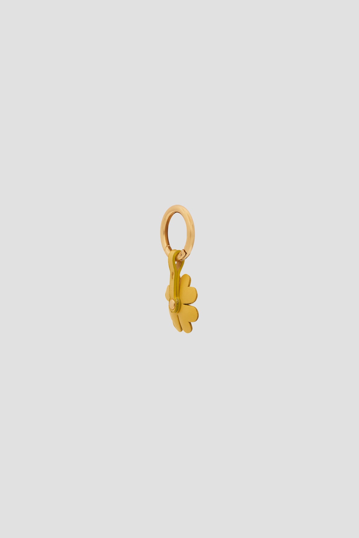 A small gold charm shaped like a daisy flower with a circular loop at the top for attaching to a bracelet or necklace, this porte-bonheur is displayed against a plain light gray background.
