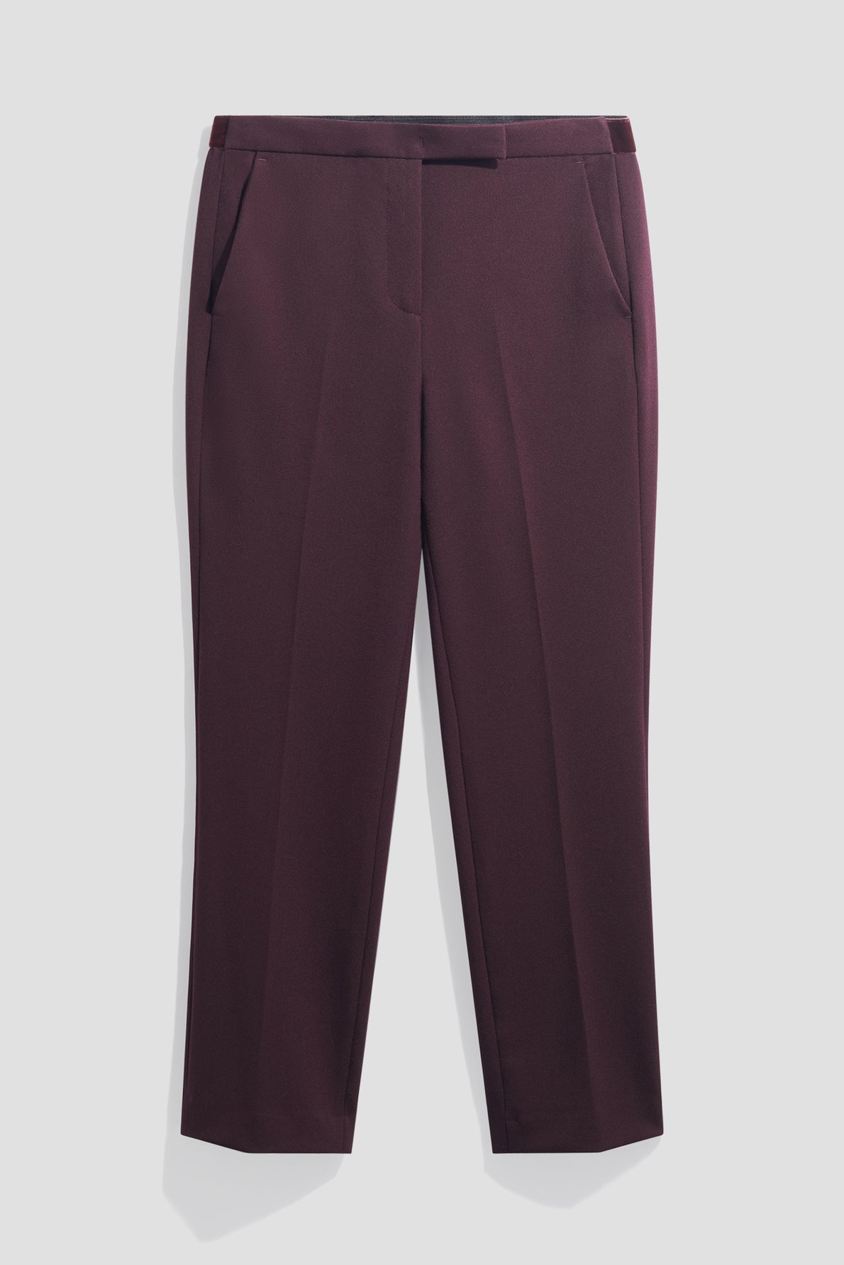 A pair of burgundy dress pants in a coupe slim silhouette with side pockets, front crease, and a flat front waistband, displayed flat against a white background. This pantalon de tailleur features a chic longueur 7/8 for an elegant, modern look.