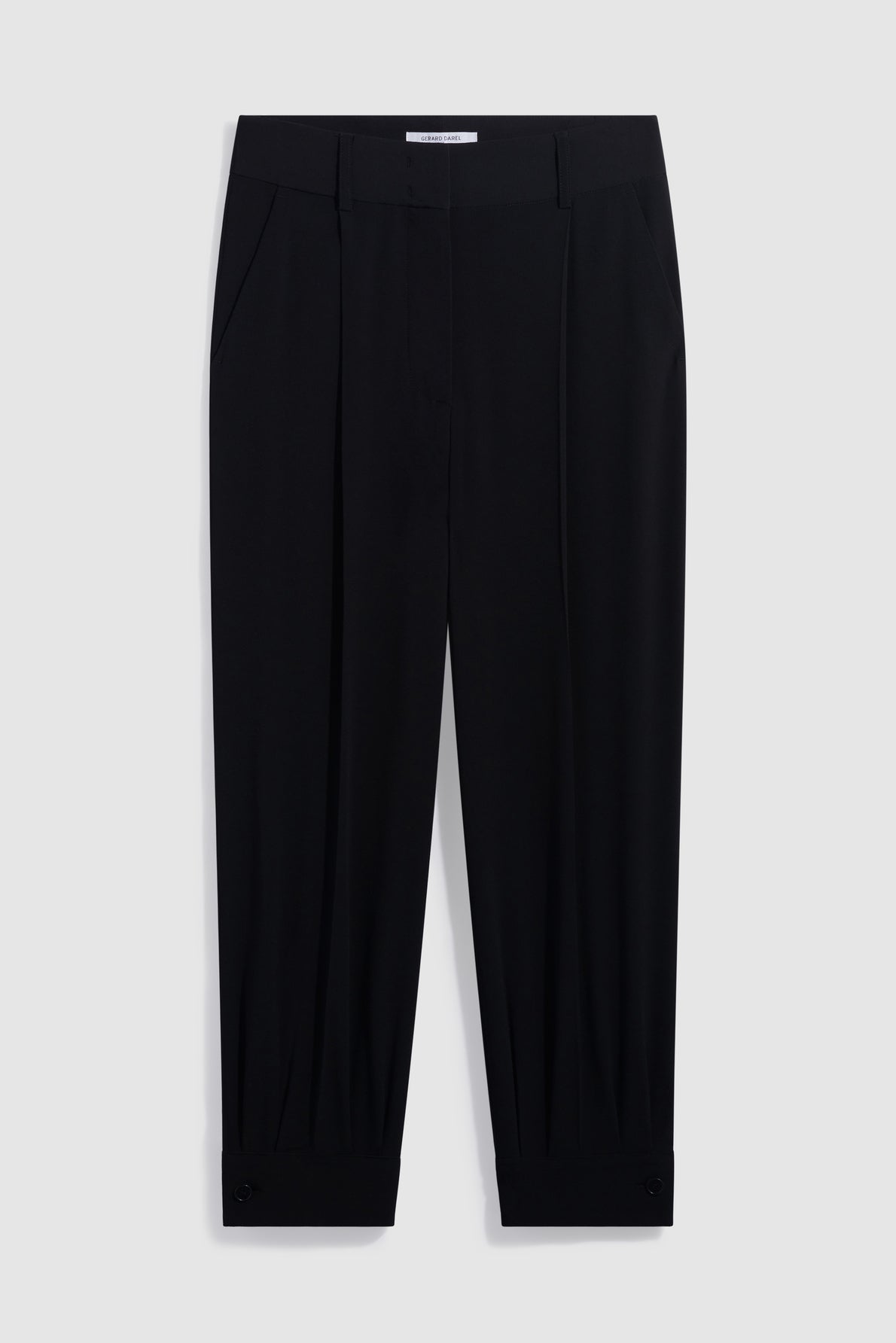 A pair of black, tailored dress pants with pleats, side pockets, and buttoned cuffs—these pantalon chic essentials capture effortless sophistication. The slightly cropped silhouette is reminiscent of a pantalon 7/8 noir, displayed elegantly against a light gray background.