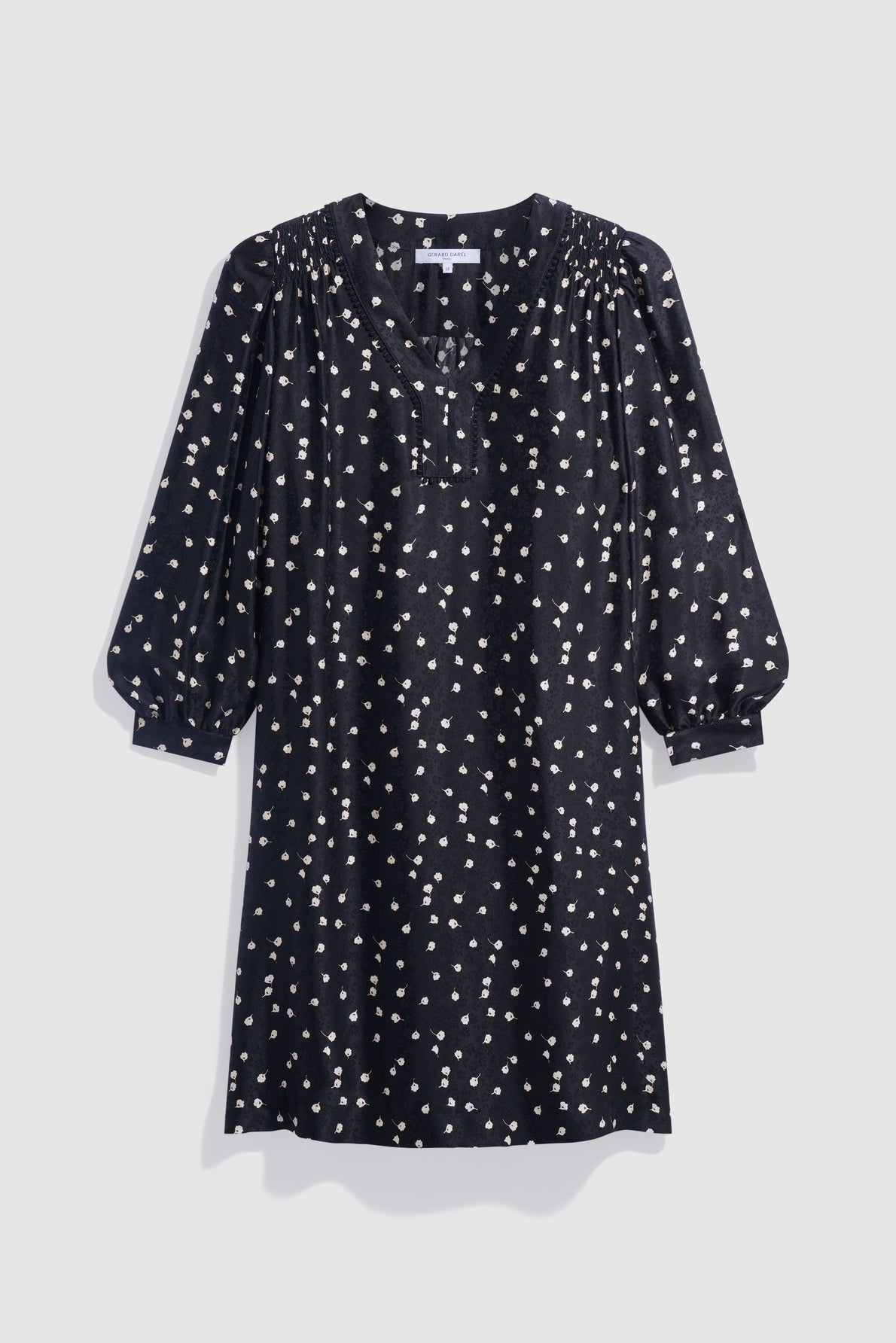 Black knee-length robe courte with a chic motif imprimé featuring white polka dots, gathered shoulders, col V, and three-quarter puff sleeves, displayed against a plain light gray background.