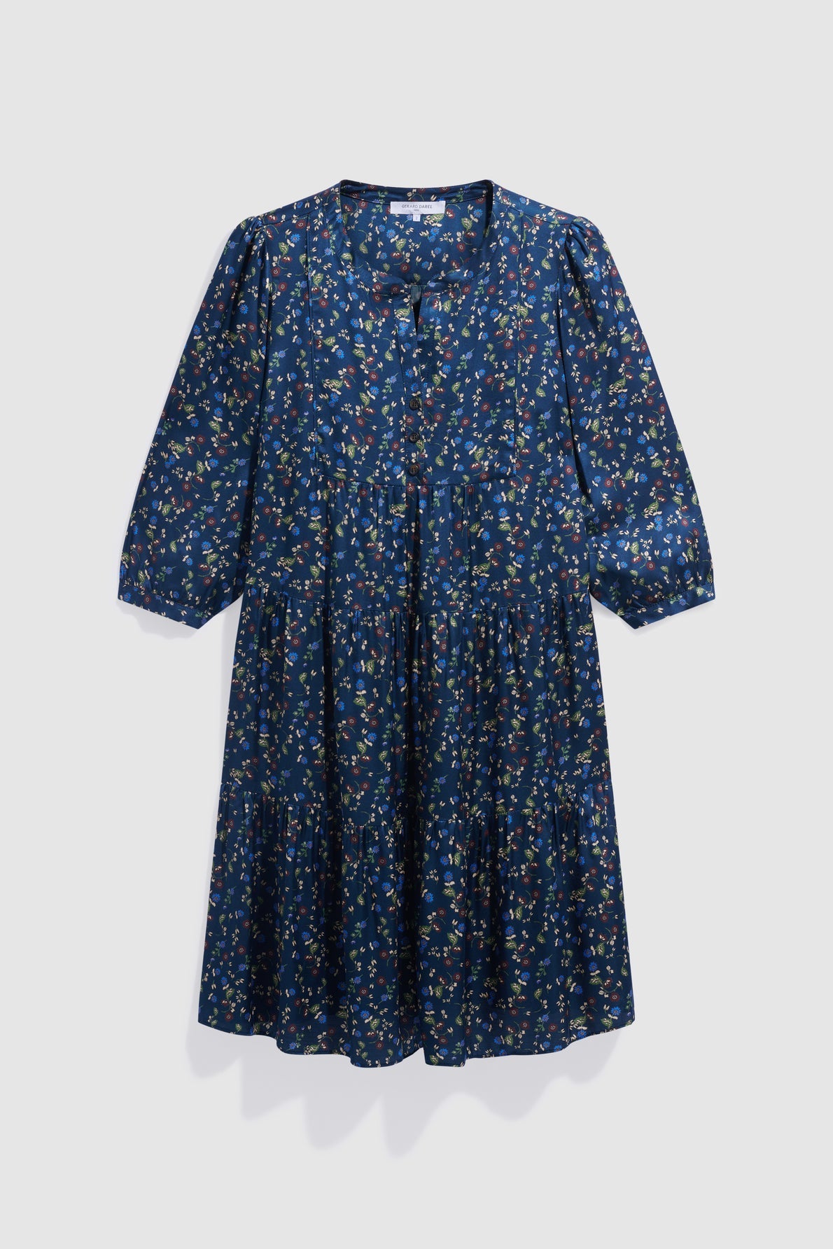 A knee-length, long-sleeve navy blue robe courte with a small floral print in green, yellow, and pink. This robe fleurie features a V-neckline, gathered waist, and a relaxed fit with slightly puffed sleeves.