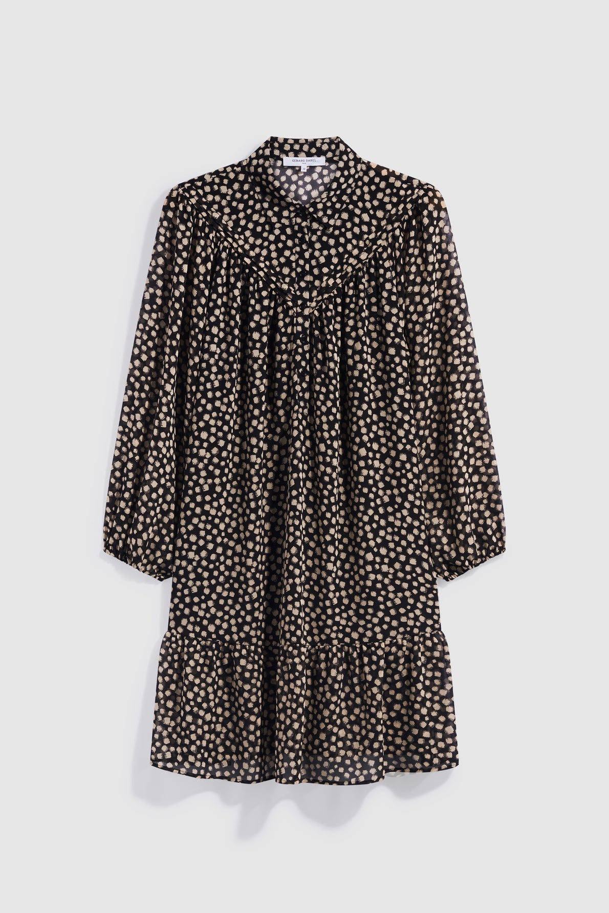 A black long-sleeve robe courte with a loose fit, featuring a tan polka dot pattern and a ruffled hem, crafted in mousseline fluide and finished with a chic col chemise, displayed against a plain light background.
