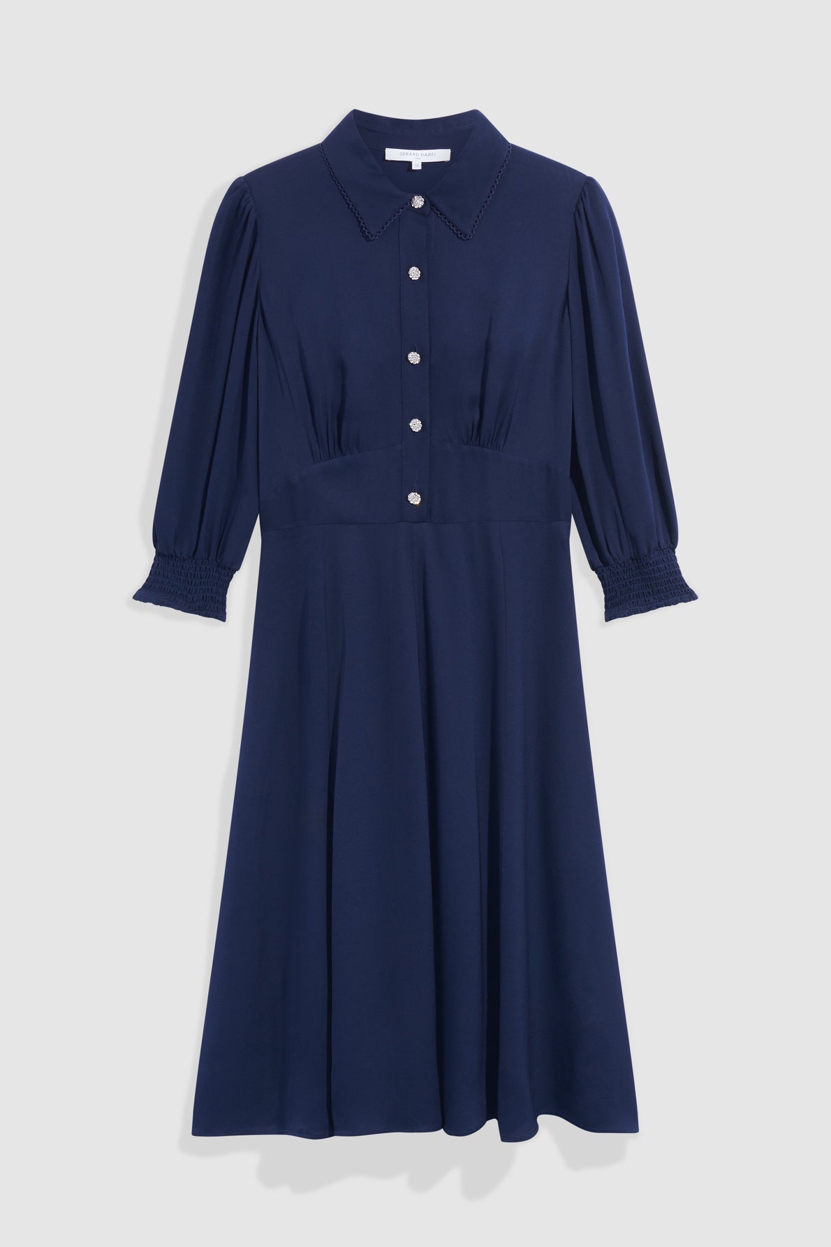 A navy blue robe midi, knee-length dress with a col chemise neckline, button-down front, puffed three-quarter sleeves with smocked cuffs, and a fitted waist. The dress has a classic, elegant style in timeless bleu marine.