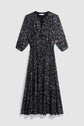 A black midi mousseline plissée dress with a multicolored motif à fleurs, V-neckline, buttons down the front, elastic waist, and elbow-length puff sleeves, displayed on a light gray background.