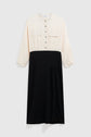 Long-sleeve robe bicolore midi featuring a cream button-up top with chest pockets and a high-waisted black skirt, displayed against a plain light background for an élégante silhouette.