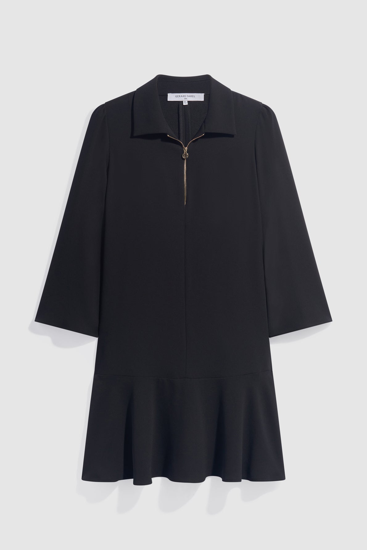A black crêpe noir long-sleeve robe courte dress featuring a col chemise, front half-zip closure, and a flared ruffle hem, displayed on a plain light background.