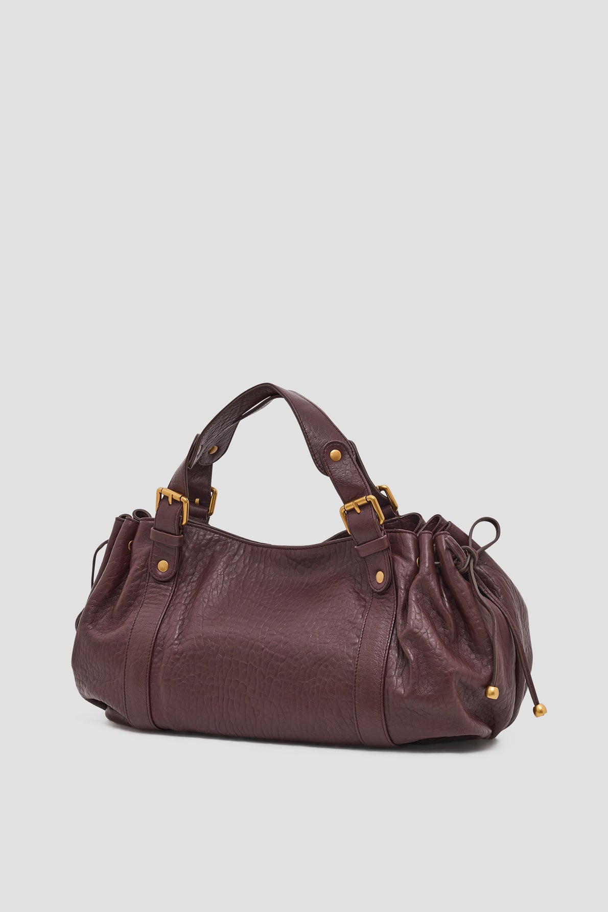 A dark purple cuir bubble leather sac à main with gold hardware, two handles, and gathered sides, displayed on a plain light background.