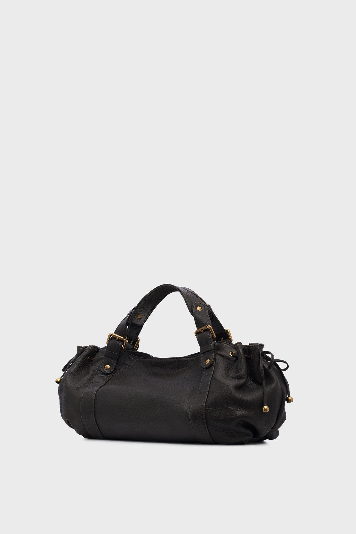 A black leather sac à main with short double handles, gold-tone hardware, and side drawstring details is displayed on a plain light gray background.
