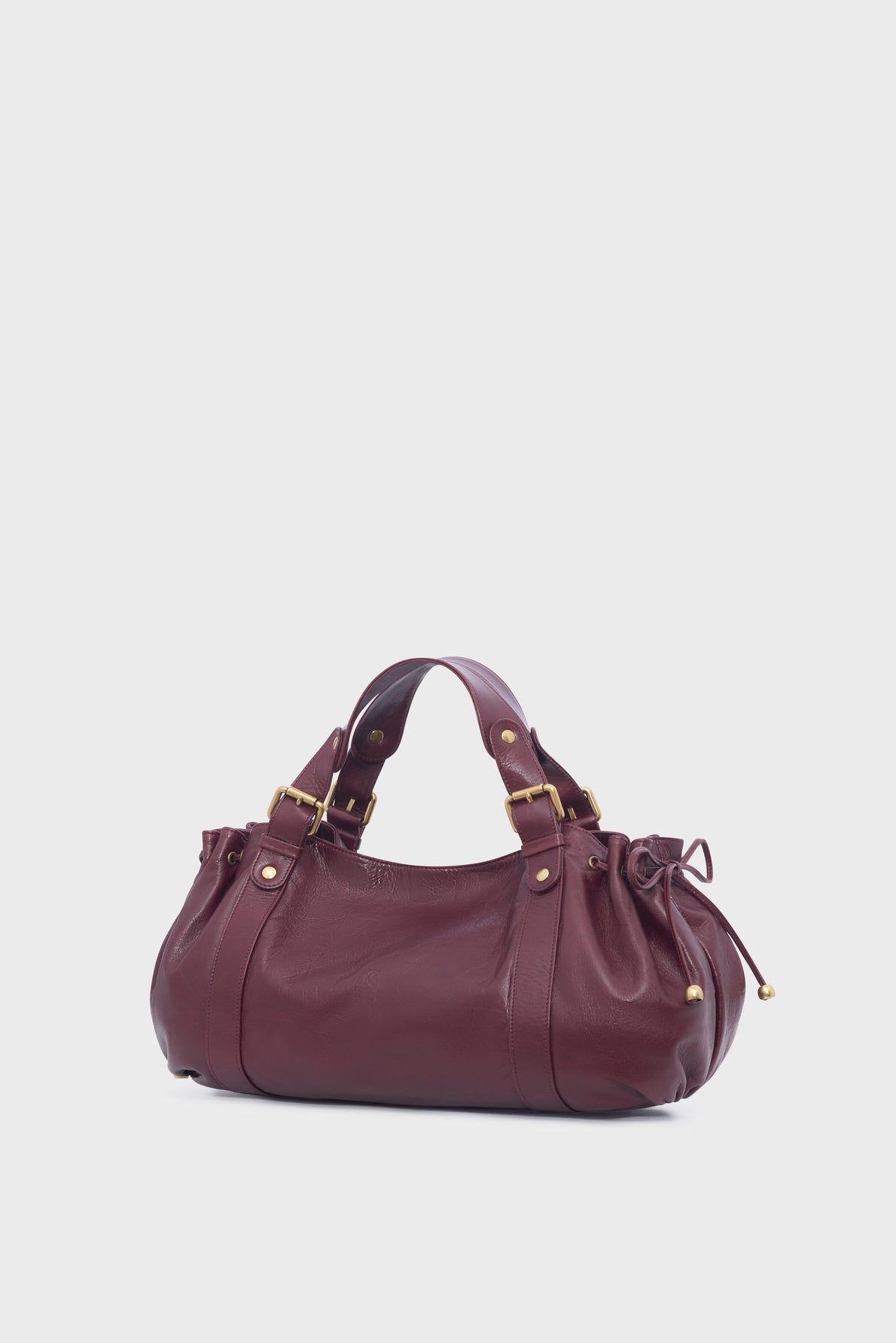 A burgundy cuir de vachette froissé leather sac à main with gold hardware, double handles, and side drawstring details, displayed on a plain light gray background.