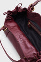Open burgundy sac à main in cuir de vachette froissé with ruffled edges, gold hardware, black fabric lining, an inside zippered pocket, and a snap button closure visible. The bag’s shoulder strap is partially shown.