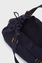 A close-up of a dark navy toile coton drawstring bag with brass hardware and shoulder straps, shown on a light gray background—perfect as a stylish sac 24H or everyday sac à main.