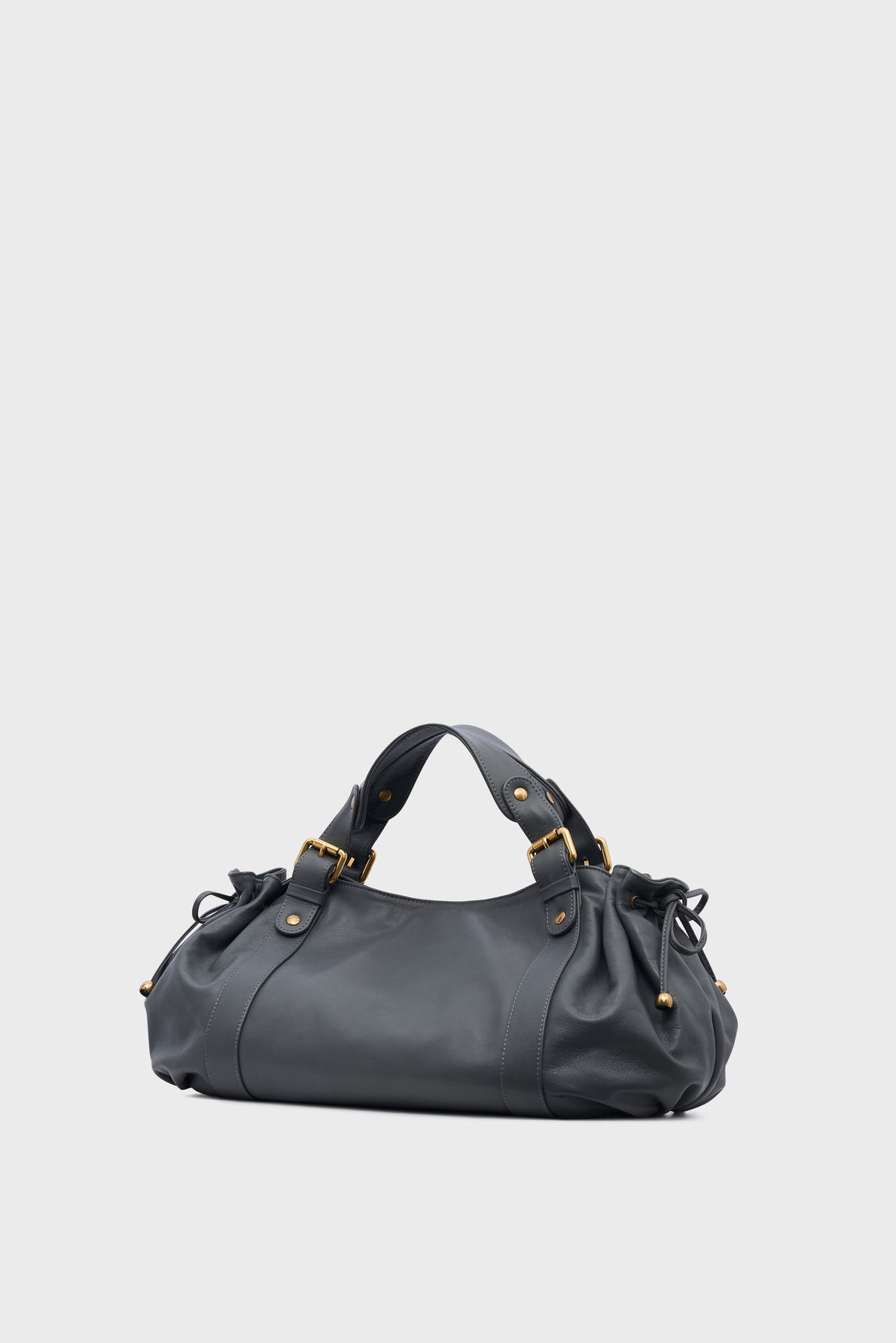 A black leather handbag with gold hardware, two handles, and gathered sides—reminiscent of the iconic sac 24H—is set against a plain light gray background, embodying the timeless elegance of maroquinerie Darel.
