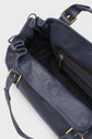 A close-up of an open navy blue leather handbag shows its spacious interior, a zippered pocket, and gold-tone hardware on the straps and zipper—an exquisite example of maroquinerie Darel craftsmanship in this sophisticated sac à main cuir.