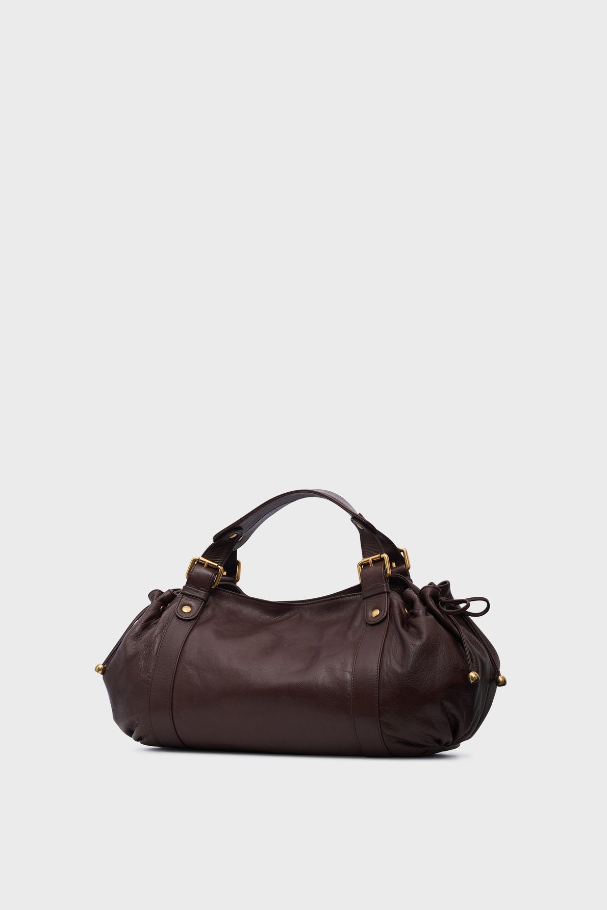 A dark brown sac à main cuir by Vanessa Bruno, featuring gold hardware, double handles, and knotted side details, displayed against a light gray background—a perfect sac 24H for everyday elegance.