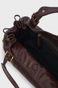 A close-up of an open brown leather handbag with gold hardware, showing a black fabric-lined interior and a zipped side pocket, evokes the timeless elegance of the sac à main cuir from Vanessa Bruno’s iconic sac 24H collection.