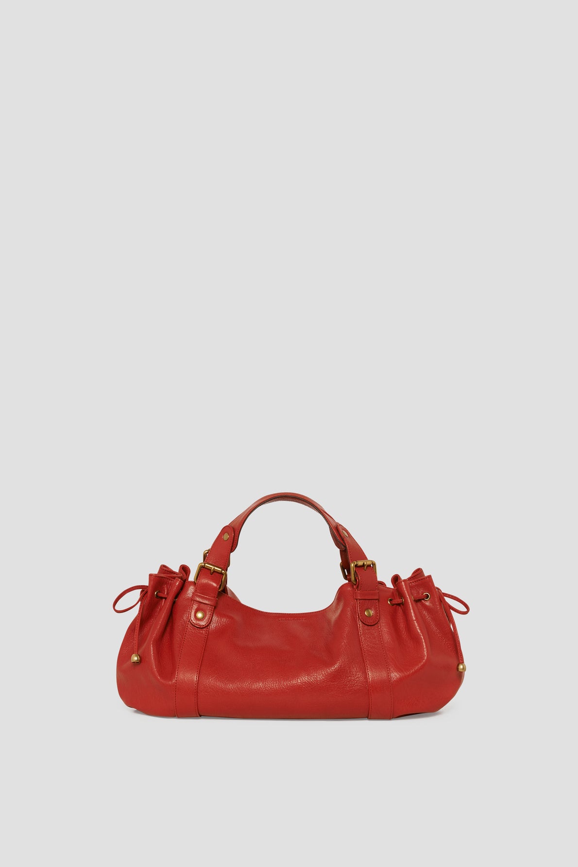 A red leather sac à main with gold-tone hardware, two top handles, and side drawstring details, set against a plain gray background—a striking example of maroquinerie Darel craftsmanship.