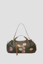 Dark green patterned handbag with two handles, gold hardware, a brown zipper tassel, and colorful travel-themed patches—including images of the Eiffel Tower and various badges—on the front. Crafted from durable toile enduite, this stylish 72H Sac de voyage is perfect for your next escapade Paris.