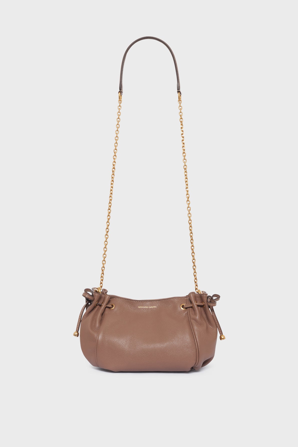Brown leather shoulder bag with gold chain strap, cinch sides, and drawstring details in luxurious cuir grainé, displayed against a plain white background. This elegant sac bandoulière from Gerard Darel exudes timeless sophistication.