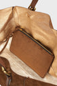 Close-up of the inside of a brown suede sac épaule handbag with gold lining, featuring an interior pocket with GERARD DAREL embossed on it and a visible zipper.