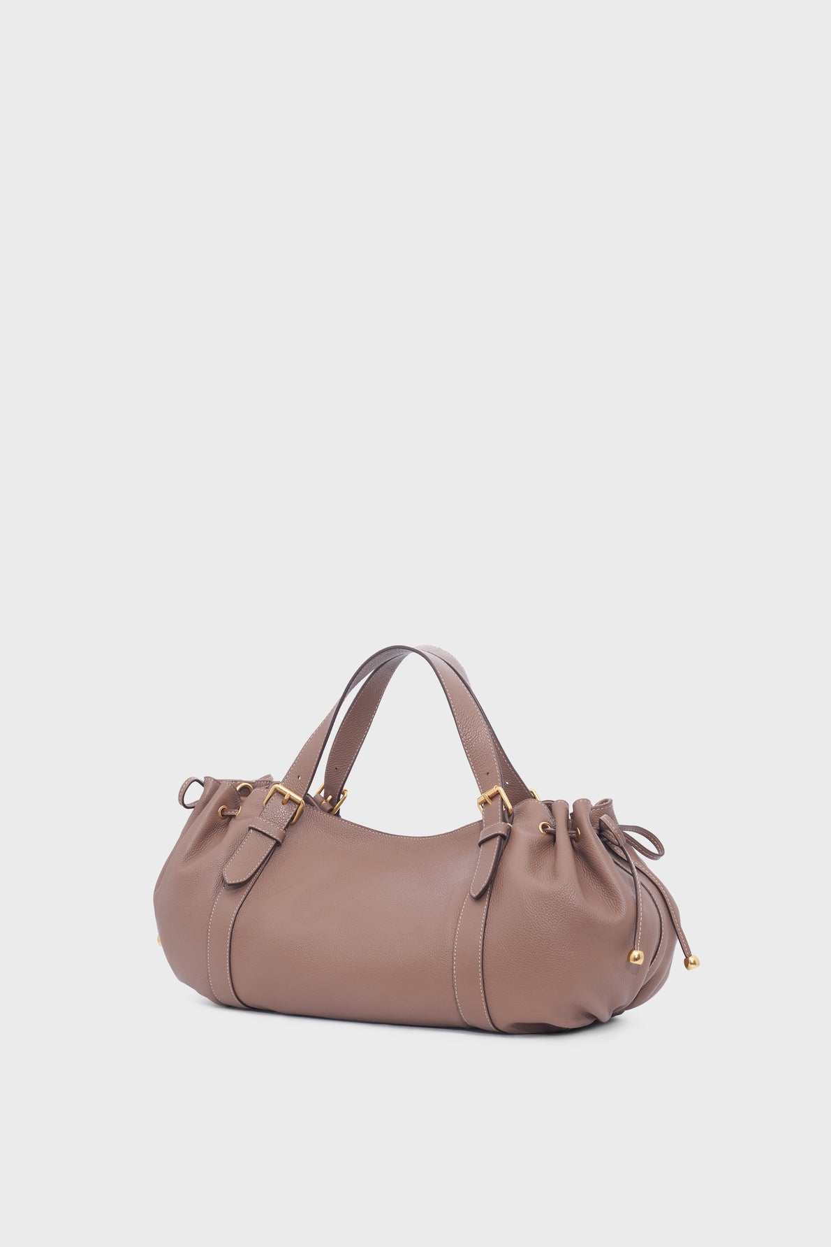Gerard Darel taupe leather sac à main with gold hardware, two short handles, and gathered side details, crafted from luxurious cuir grainé and placed against a plain white background.