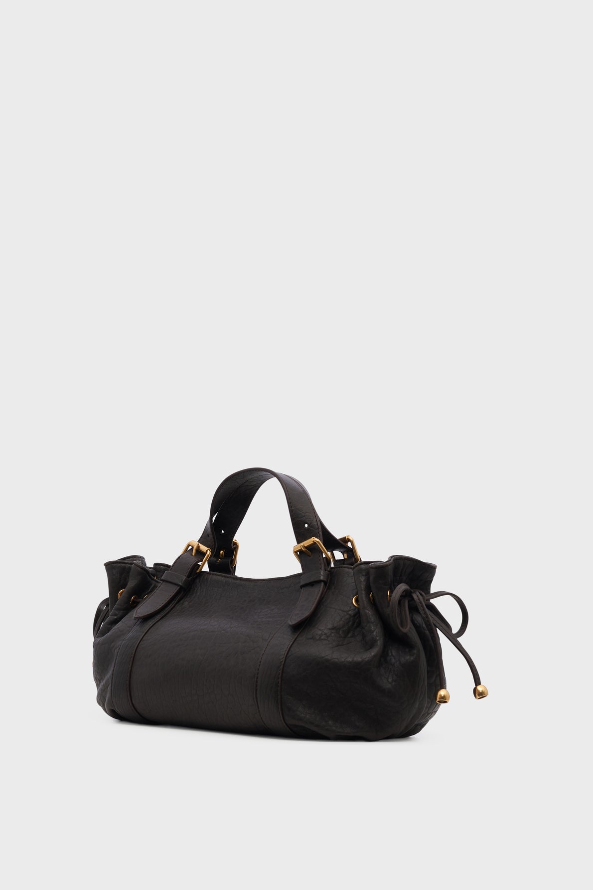 Black leather sac à main with gold hardware, two short handles, and drawstring details on each side, displayed against a plain light gray background.
