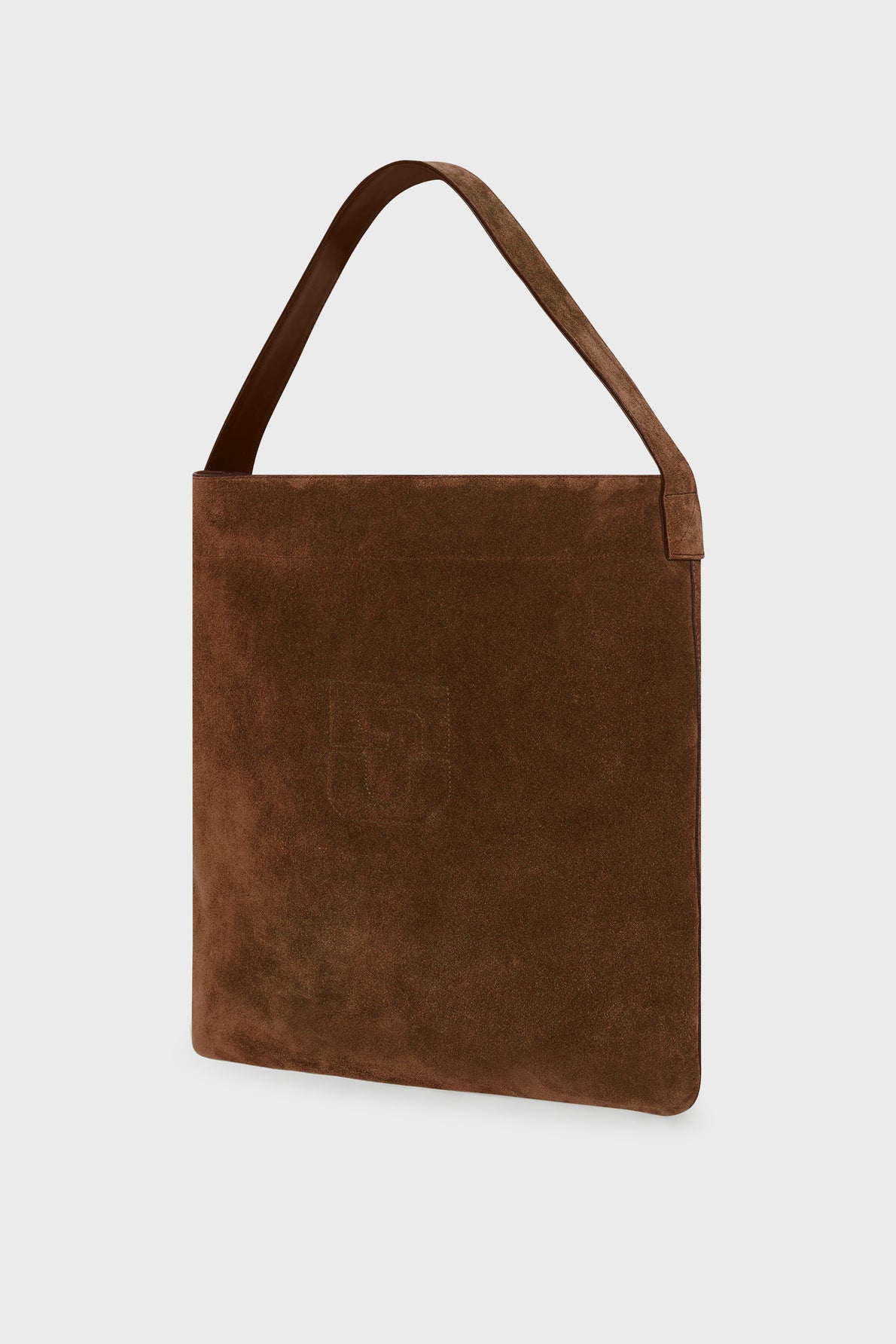 Brown suede shoulder bag in cuir velours with a wide strap, minimalist design, and subtle embossed logo on the front, photographed against a plain light background.