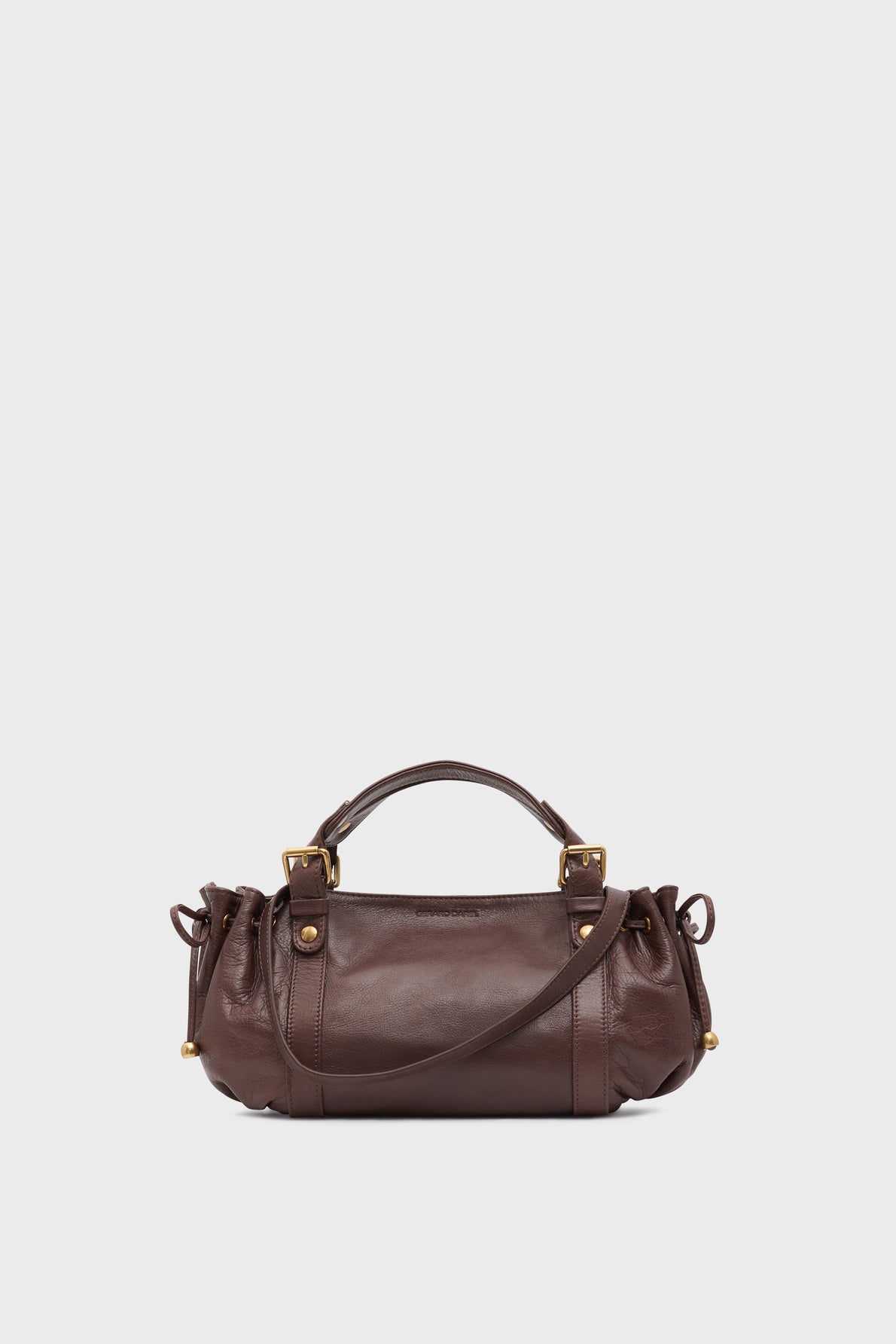 A small brown sac à main crafted from premium cuir de vachette, featuring gold hardware, two short handles, side drawstring details, and a long crossbody strap—an elegant it-bag 24H set against a plain white background.