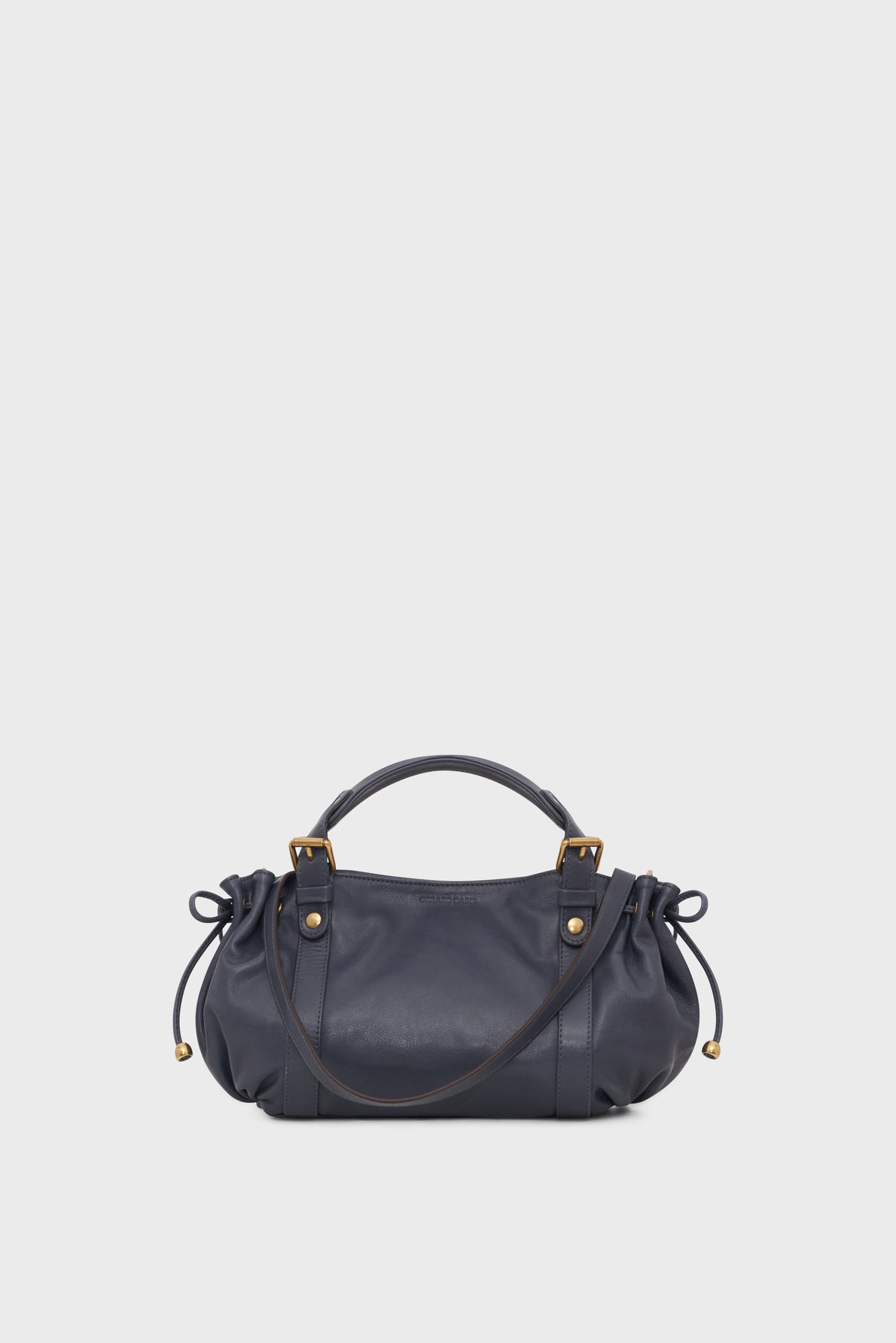 A navy blue leather sac à main with gold hardware, two handles, and gathered sides tied with drawstrings, set against a plain light gray background. Featuring a bandoulière amovible for versatile carrying options.