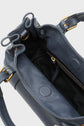 A close-up of the open interior of a blue leather sac à main with gold hardware, showing a black fabric lining and a zippered pocket inside; this elegant handbag also features a bandoulière amovible for versatile carrying options.