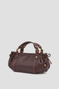 A dark brown cuir sac à main in a format mini, featuring gold hardware, two handles, side drawstring details, and a slightly gathered design, set against a plain light gray background.