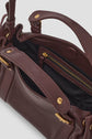 A close-up of an open burgundy cuir sac à main with gold hardware, showing black fabric lining and a zippered inner pocket in a chic format mini.