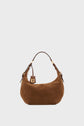 Brown suede cuir velours sac hobo handbag with a rounded shape, short dark brown leather handle, and gold hardware details. A leather tag with a gold logo hangs on one side, adding a touch of chic parisienne flair. The background is plain white.
