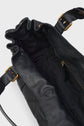A close-up of an open black leather sac à main with a fabric-lined interior, gold-tone hardware, and an adjustable shoulder strap. The bag is empty and the inside details are clearly visible, showcasing its savoir-faire d’exception.