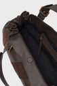 Open brown leather sac à main with a suede accent, showing a black fabric-lined interior, an inner zippered pocket, and a magnetic snap closure. The strap features gold-tone hardware and subtle cuir patchwork details for added sophistication—perfect for 24H style.