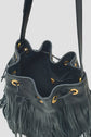 Black leather bucket bag with fringe detailing, gold grommets, drawstring closure, and long shoulder strap. This sac seau cuir noir embraces a bohème-chic flair, while the bag is open to reveal its unlined interior.
