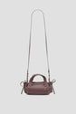 A small, dark brown cuir leather Micro 24 sac bandoulière with a long, adjustable shoulder strap and two short handles, displayed against a plain light background.