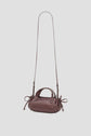 A small, dark brown cuir leather sac bandoulière handbag with a long shoulder strap, two short handles, and side drawstring details, displayed against a plain light gray background.