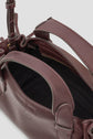 A close-up view of a burgundy cuir leather handbag, featuring double handles and an open top, reveals the black interior lining and a zippered pocket inside—ideal as a chic sac bandoulière in the coveted Micro 24 size.