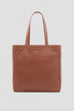 Brown leather tote bag cuir with GERARD DAREL embossed on the front. The bag has two handles and a simple, minimalist design, displayed against a light gray background—an elegant Merci Paris essential by Gérard Darel.