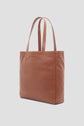 A tan leather tote bag with two shoulder straps, featuring the embossed brand name Gérard Darel on the front, is displayed against a light gray background. This elegant tote bag cuir effortlessly embodies the chic Parisian style associated with Merci Paris.