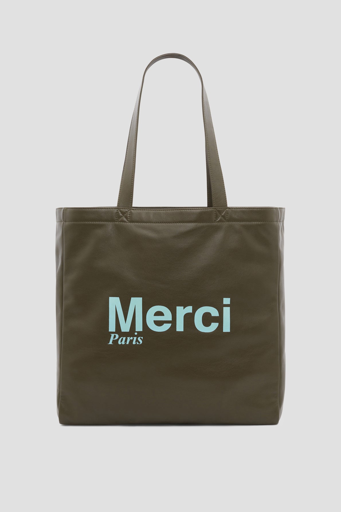 A dark olive green tote bag Merci Paris with two handles and the words “Merci Paris” printed in light blue on the front, inspired by the elegant cabas cuir Gérard Darel style.