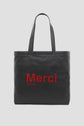 A black tote bag with two handles, featuring the word Merci in large red letters and Paris in smaller red text underneath on the front, inspired by the elegant style of Gérard Darel. Perfect for adding a touch of Merci Paris charm to your everyday look, this design evokes the classic appeal of a tote bag cuir.