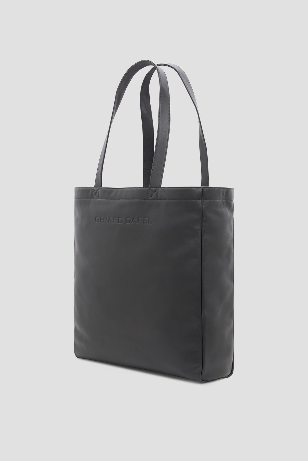 A black tote bag cuir with double handles and Gérard Darel embossed on the front, photographed against a plain light gray background.