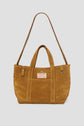 Brown suede tote bag (cuir velours) with a long shoulder strap and two short handles. This elegant cabas Gérard Darel features a front patch with the text GERARD DAREL MERCI DE PARIS and a silver ring on one side, making it the perfect sac Merci for everyday style.
