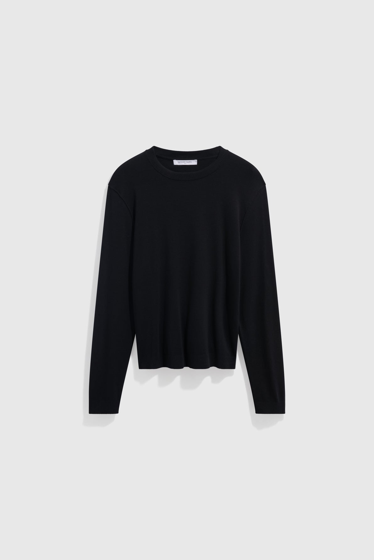 A plain black long-sleeve crew neck sweater, crafted from coton épais for extra warmth, is displayed on a light gray background.