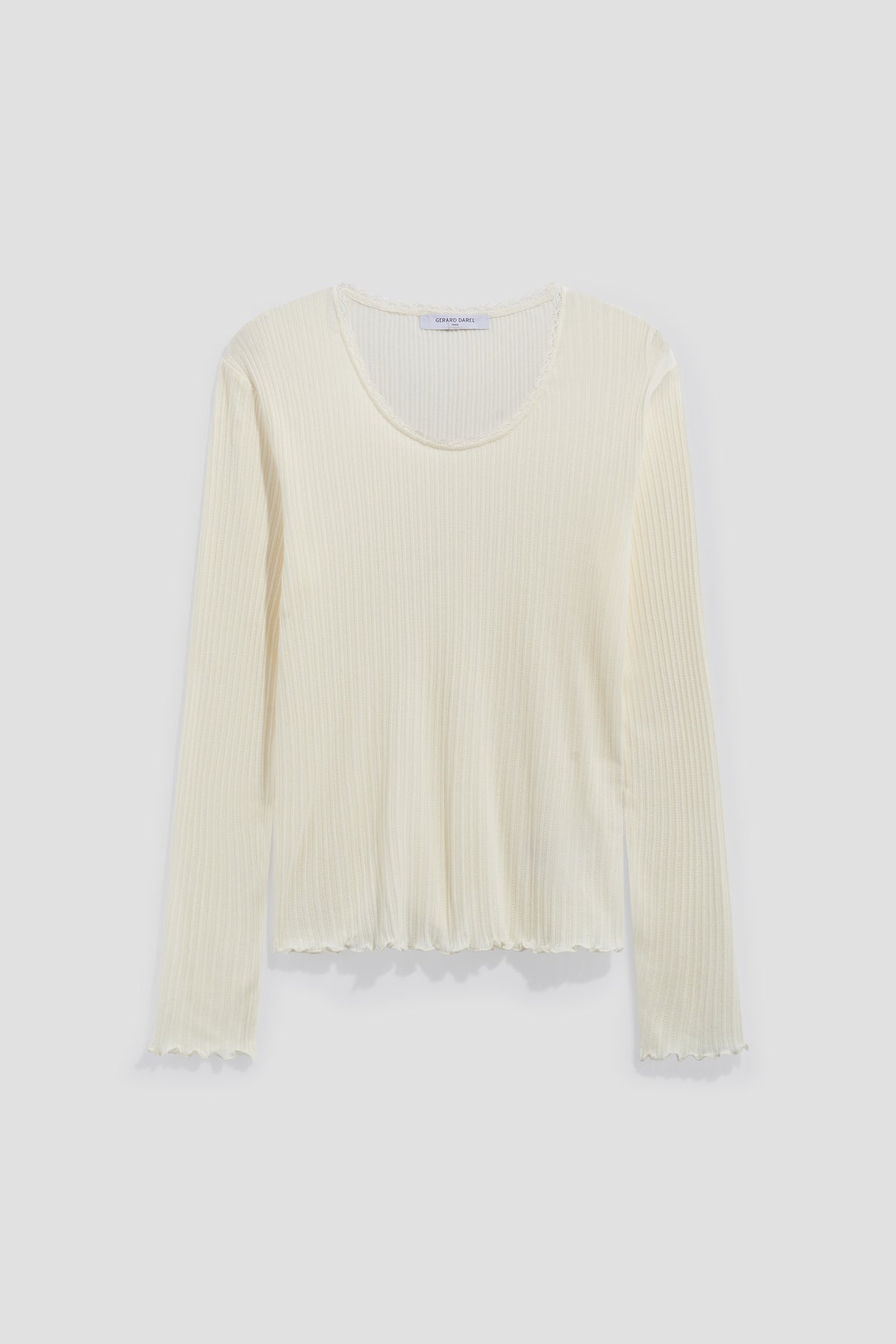 A long-sleeve, cream-colored ribbed top crafted from mailles côtelé, featuring a round neckline and subtle scalloped edges on the cuffs and hem, displayed on a plain light background.