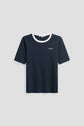 Navy blue short-sleeve tee-shirt bleu marine in soft coton, featuring a crisp white col contrasté crew neck collar and small white embroidered text on the left chest, displayed on a plain light gray background.