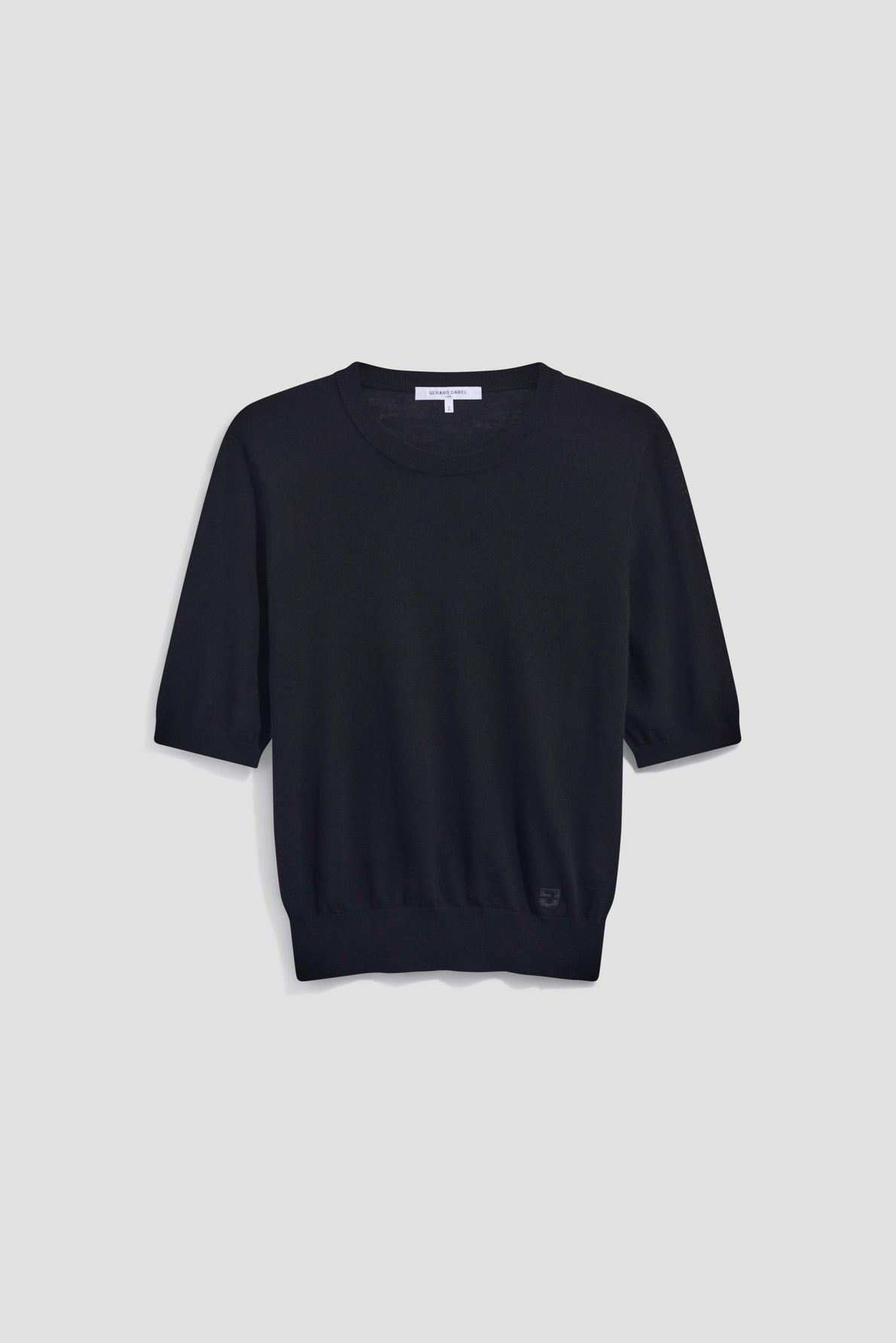 A plain black short-sleeve knit sweater in soft laine mérinos with a classic pull col rond, displayed on a light gray background.